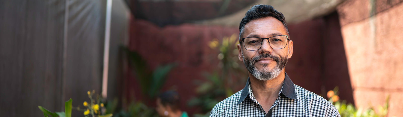 A man in a greenhouse smiling at the camera