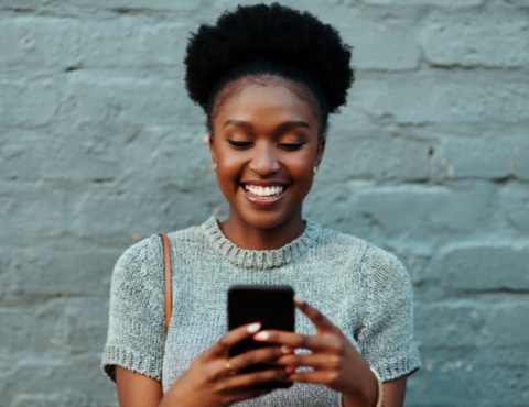 A young woman smiling and holding a smartphone