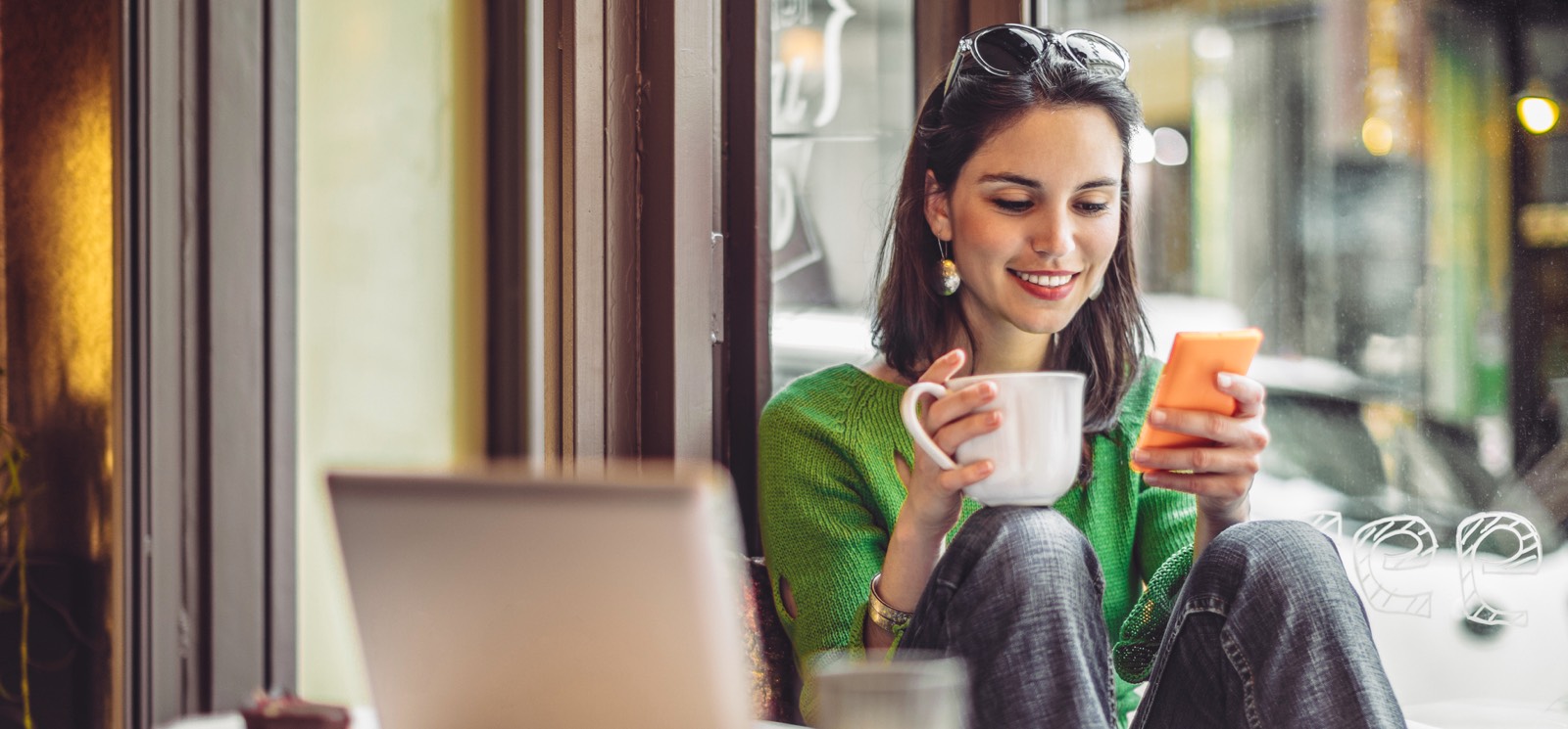 A young woman holding a coffee and a smartphone