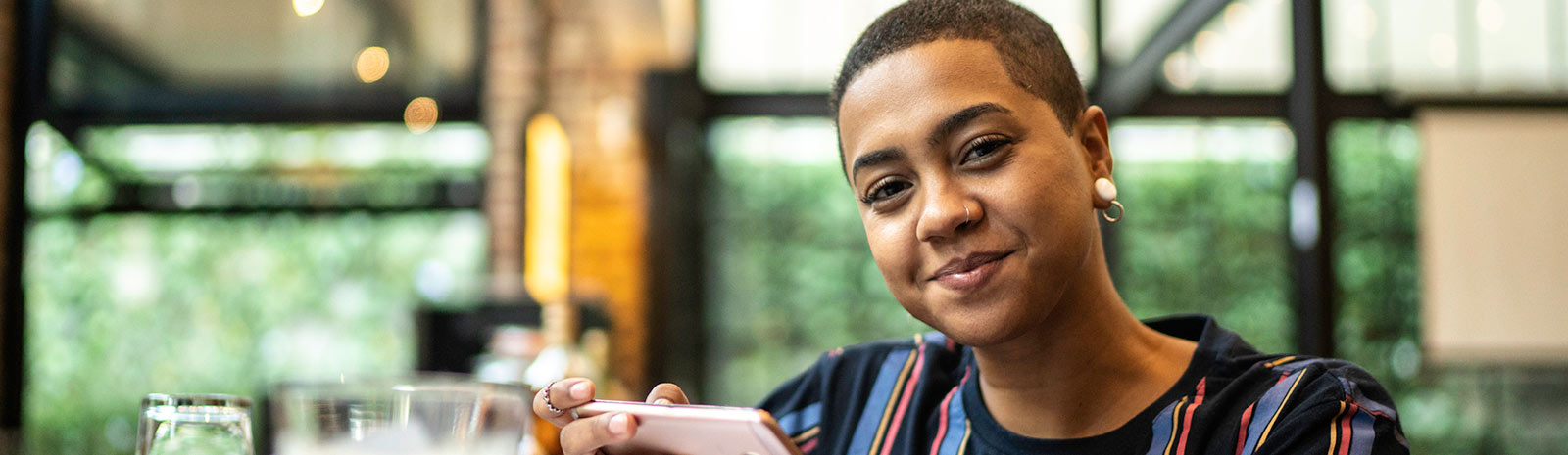 A woman holding a smartphone and looking at the camera